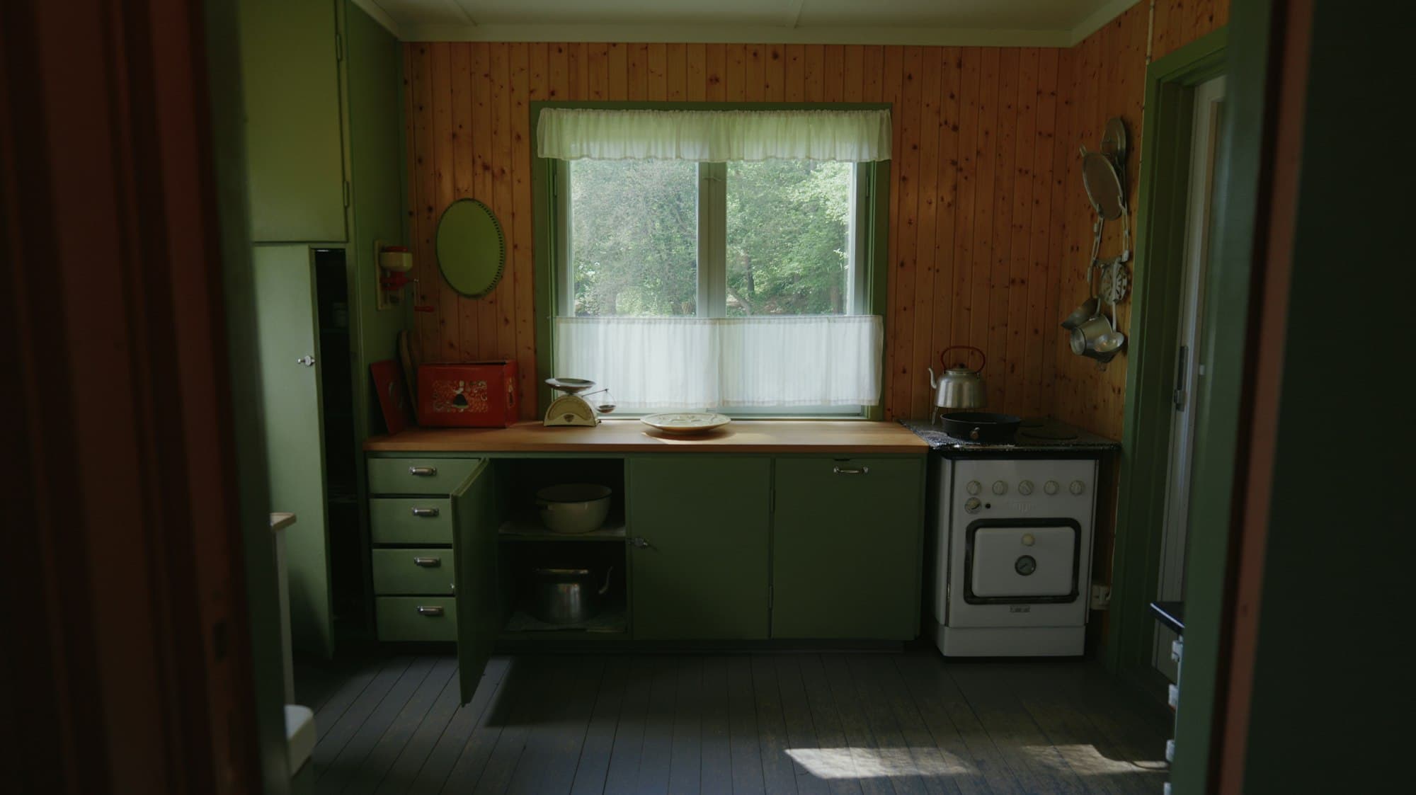 Antes: cocina antigua con muebles verdes y paredes de tablas de pino.
